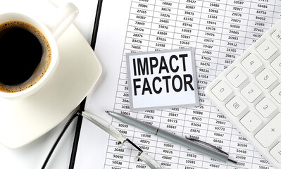 IMPACT FACTOR text on sticky on the chart with coffee,pen and calculator