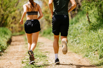 Fototapeta premium Sport people running in park together. Young couple jogging at outdoor workout. Fitness woman and man running marathon at sunset in park