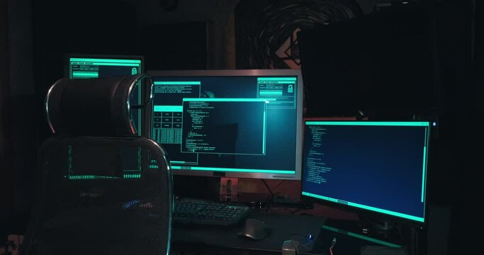 Hacker workplace has three monitors, the room is dark, there are no people. Concept of cyberterrorism, server hacking and cyber attacks