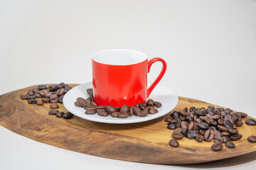 Roasted coffee grains near aged wooden plate and coffee cup on white background