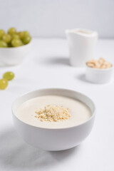 Crema de almendras, sopa fría española. Ajo blanco de Málaga con almendras y uvas en un recipiente blanco sobre una mesa blanca