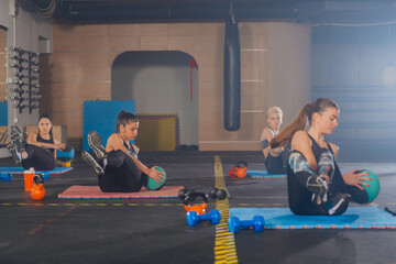 Attractive sports girls practicing abs exercise with med ball in a group fitness workout
