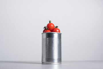 Tomates cherry enteros dentro de una lata de conservas sobre fondo gris	