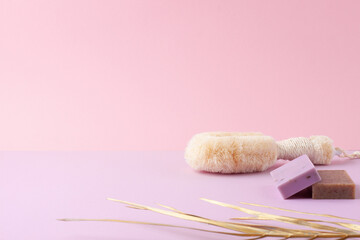 Brush and soap with palm leaf on pink background. Close up, copy space