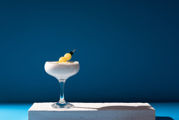 Crema de almendras, sopa española fría. Ajo blanco malagueño con almendras y uvas servido en un vaso sobre fondo azul	