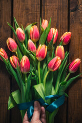 A bouquet of tulips lies on a brown wooden background