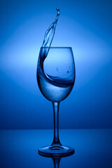 Splash of water in a glass on blue background