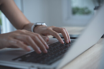 Closeup image of a business woman's hands working and typing on laptop computer keyboard on glass...