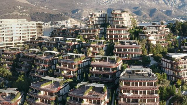 Luxury apartment buildings on the hillside - homes with view. Residences in a vacation tourist destination on the Mediterranean sea coast. Rooftops of green eco houses - aerial drone view on sunny day
