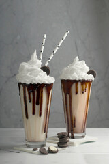 Delicious dessert drink. Chocolate milkshakes with whipped cream, cookies in a tall glass on a light background. Selective focus