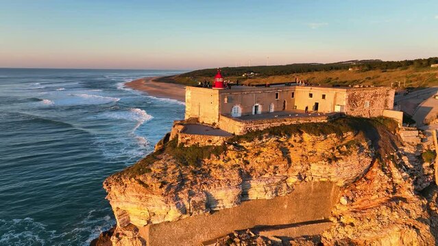 Top view of the lighthouse on the rock near the Atlantic ocean. Rocky Atlantic seashore in Portugal. Aerial view of the lighthouse in Nazare, Portugal.