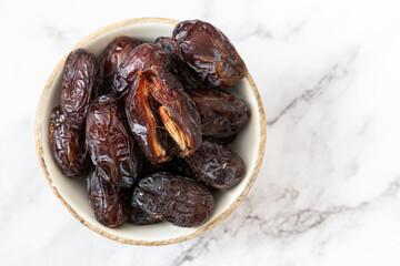 Organic Medjool Dates in a wooden bowl on white background	
