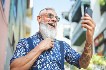 Happy  senior man having fun using mobile smartphone outdoor