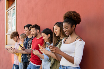 Young multiracial group of friends using mobile smartphone outdoor - Millennial generation having fun with new trends social media apps - obrazy, fototapety, plakaty