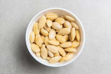 peeled almonds in a white cup on a concrete background. concept for a recipe for making almond flour. top view