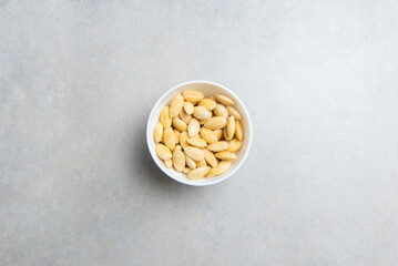 peeled almonds in a white cup on a concrete background. concept for a recipe for making almond flour. top view