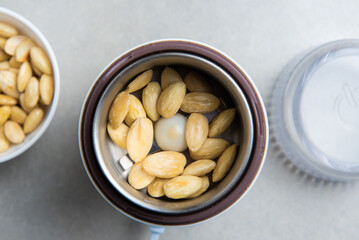 peeled almonds in a coffee grinder on a concrete background. concept for a recipe for making almond flour. top view