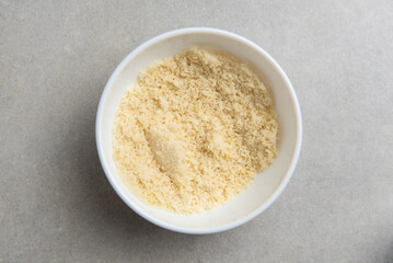 freshly ground almond flour in a white bowl on a concrete background. concept for a recipe for making almond flour. top view