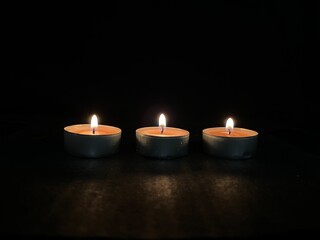 Fototapeta na wymiar Burning scented candles isolated on black background.