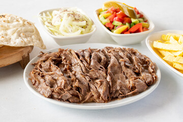 Doner kebab on a white background. Traditional Turkish cuisine flavor meat doner. With lavash bread, french fries, salad and onions on the side