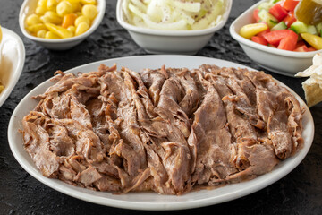 Doner kebab on a dark background. Traditional Turkish cuisine flavor meat doner. With lavash bread, french fries, salad and onions on the side