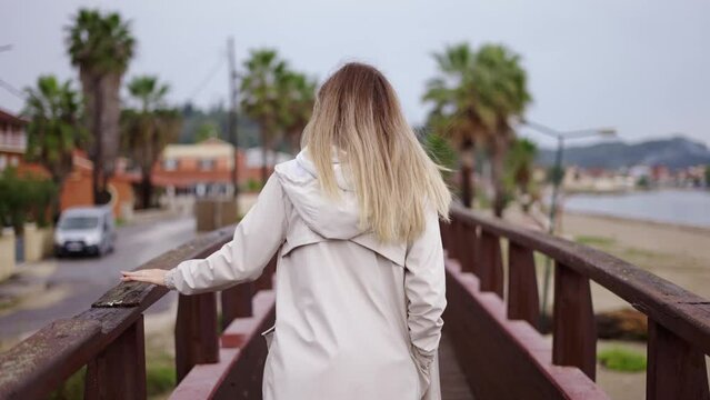 Blonde woman walking on small wooden bridge in a small city