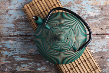 Beautiful green japanese cast iron teapot on bamboo mat