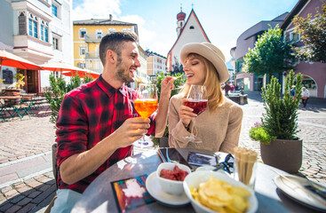 Happy couple taking an aperitif in a cafè. - obrazy, fototapety, plakaty