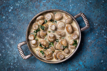 Frying pan of mushrooms in cream sauce with spinach