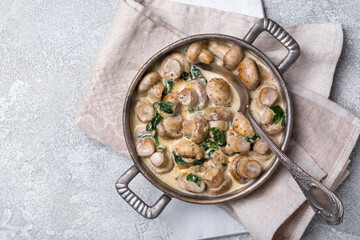 Frying pan of mushrooms in cream sauce with spinach