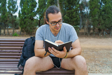 Fototapeta premium Man sitting in a park writing in a notebook