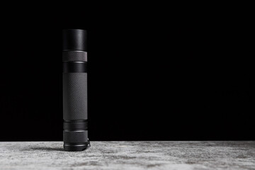 Flashlight stands on a table on a black background with copy space
