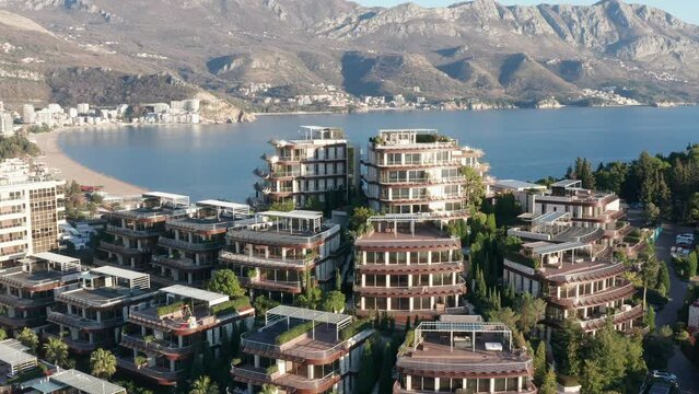 Luxury apartment buildings on the hillside - homes with view. Residences in a vacation tourist destination on the Mediterranean sea coast. Rooftops of green eco houses - aerial drone view on sunny day