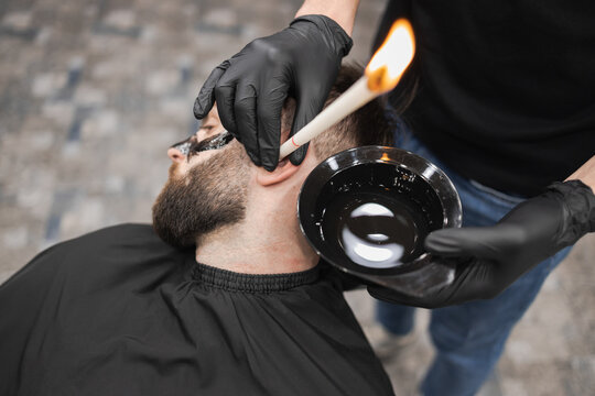 Man in a beauty salon is removing earwax using candles. Male enjoying a spa treatment