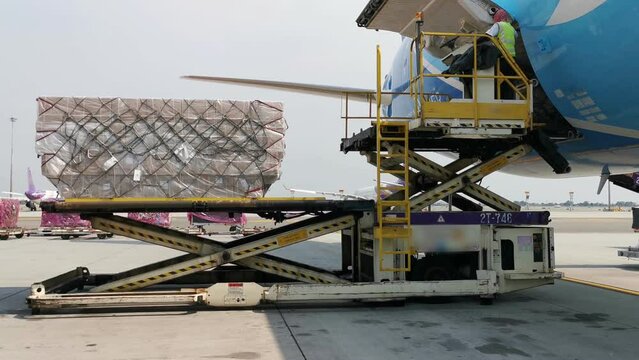 A worker is loading a cargo containers from the freighter airplane at the airport. In the logistic industry the air transport is very popular.