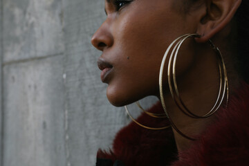 Headshot of young beautiful African American woman poses on concrete background.