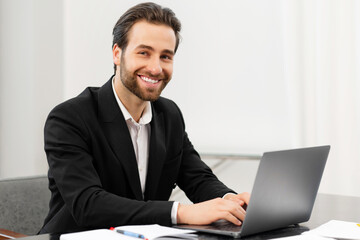 Fototapeta na wymiar Happy smiling business man working from office. Successful male sitting at the desk, using laptop, develop a project. Workplaces concept