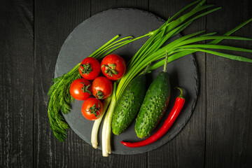 Big set for fresh vegetable salad. Red tomatoes and green young onions with cucumber on a vintage brown plate