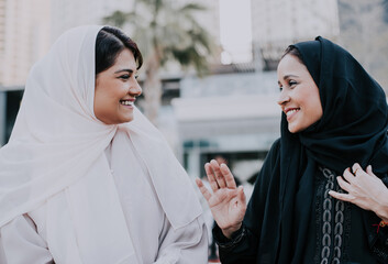 Two arabian girls spending time together outdoor making activities. Young women making shopping in Dubai