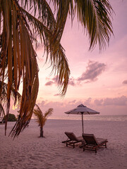 Panoramic tropical sunset scenery, two sun beds, loungers, umbrella under palm tree. White sand,...