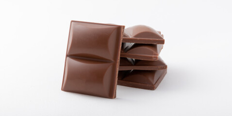 Cubes of delicious milk chocolate isolated on white background.