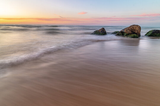 Low angle wide view of the waves crashing on the rocks during sunset at the sea Poleg beach Israel. 
