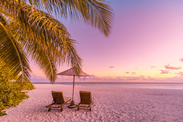 Panoramic tropical sunset scenery, two sun beds, loungers, umbrella under palm tree. White sand, sea horizon view colorful sunrise sunset sky calm relax mood. Summer couple vacation beach resort hotel