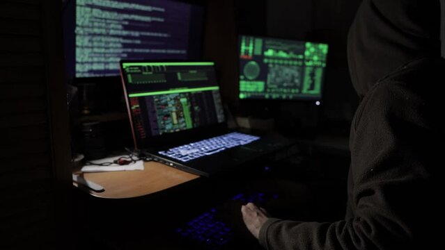 a hacker in a dark room in front of a monitor is trying to hack the security system
