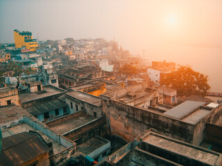 Scenery of colorful ruined slums and other historical buildings on the banks of river Ganges during sunset in Varanasi, India.