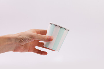 A man's hand holds a paper disposable cup on a white background. Close-up. Copy space.