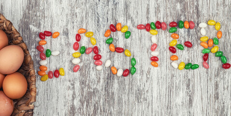 On a wooden countertop with small colored sweets laid out the word Easter