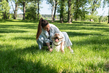 Young student woman professional dog or pet walker walking the dog Labrador Retriever outdoor while the owner is on the work. Cute female enjoying with her puppy friend in the park.