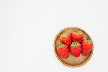 A space with a pure white background, lots of strawberries served in a wooden bowl.