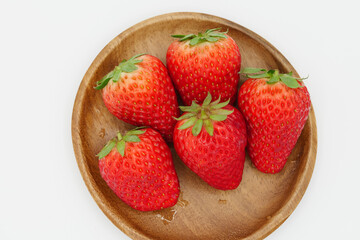 A space with a pure white background, lots of strawberries served in a wooden bowl.